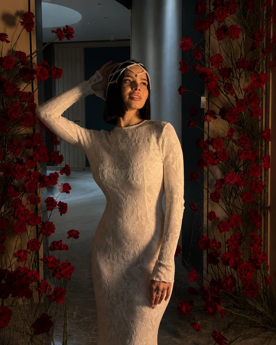 Inessa Bertta standing within a sculptural red rose installation