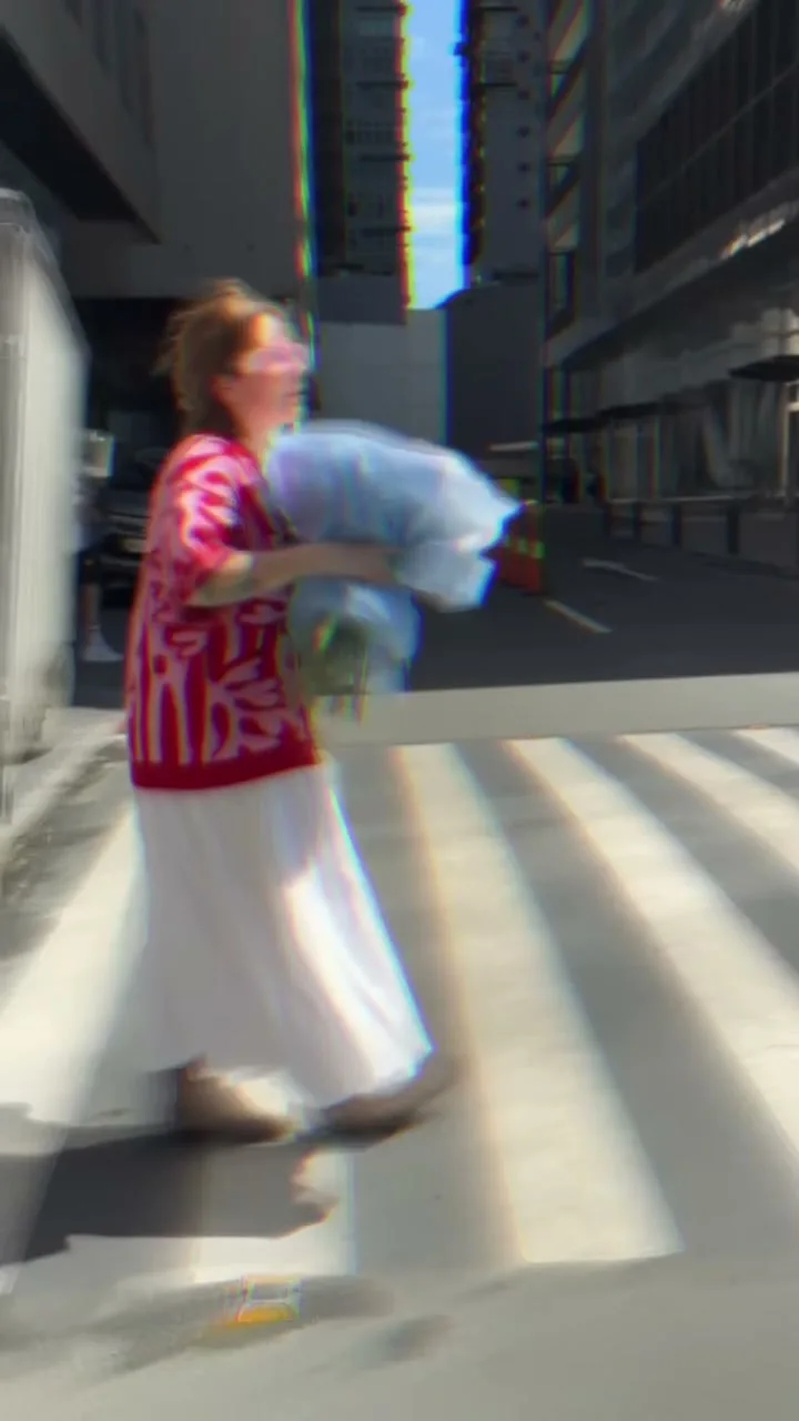 Woman carrying an oversized blue Holy Chic bouquet through the city