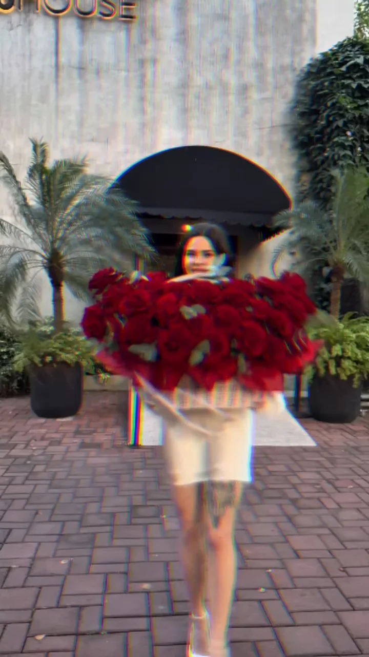 Woman carrying an oversized Holy Chic bouquet of red roses