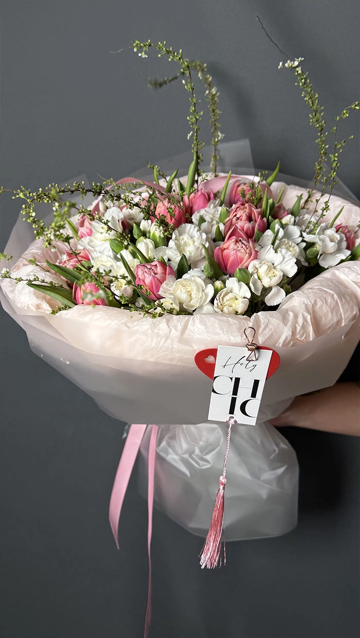 A round mixed bouquet of tulips and dianthus with branches